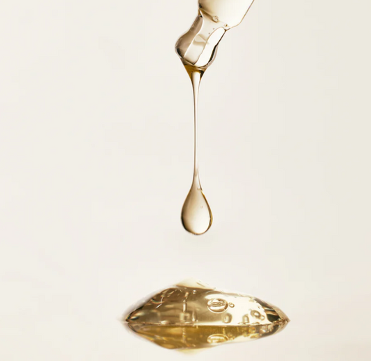 Gold droplet and puddle on a light beige background
